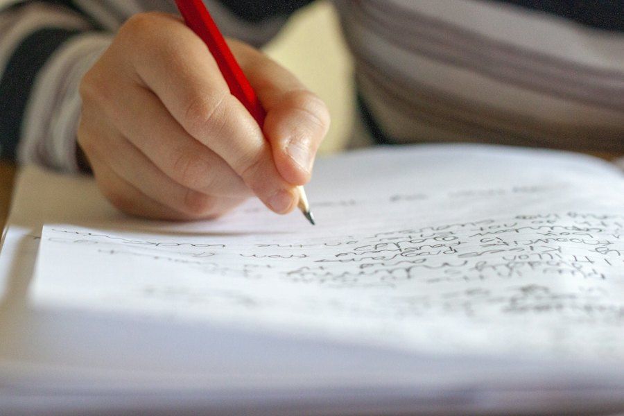 Mano escribiendo a lápiz sobre un cuaderno
